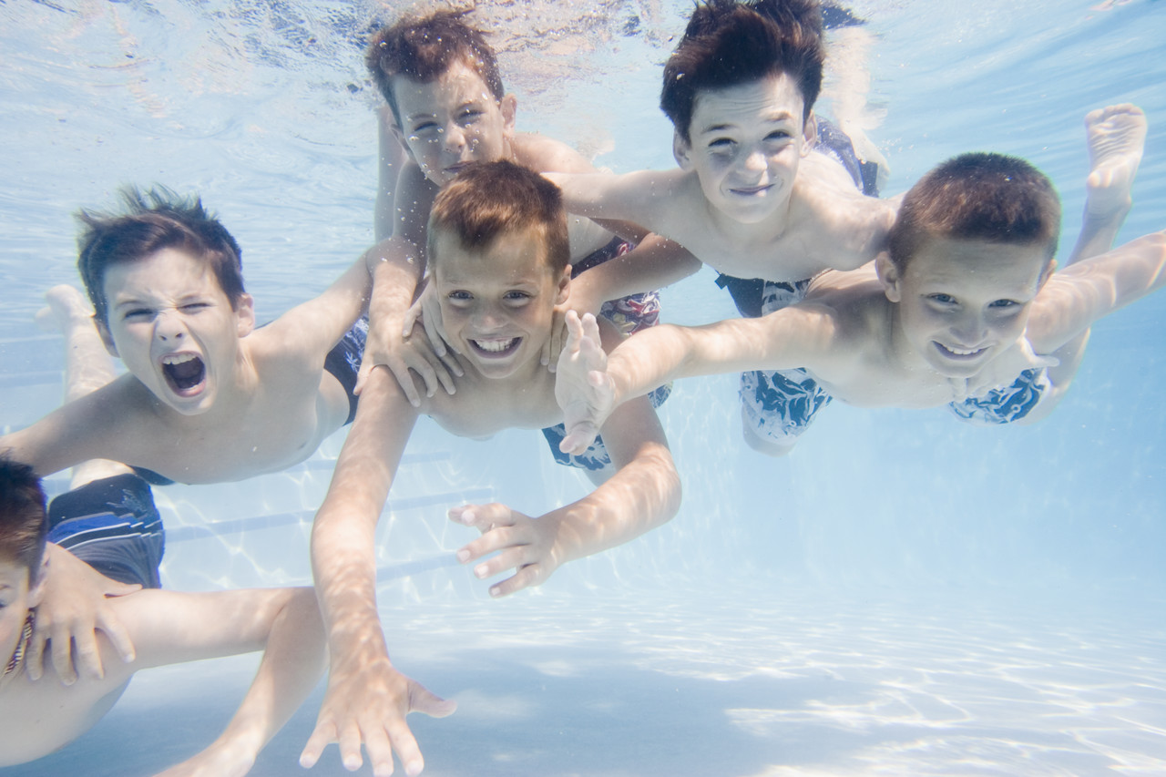 Friends Swimming Underwater in Backyard Pool --- Image by © Royalty-Free/Corbis