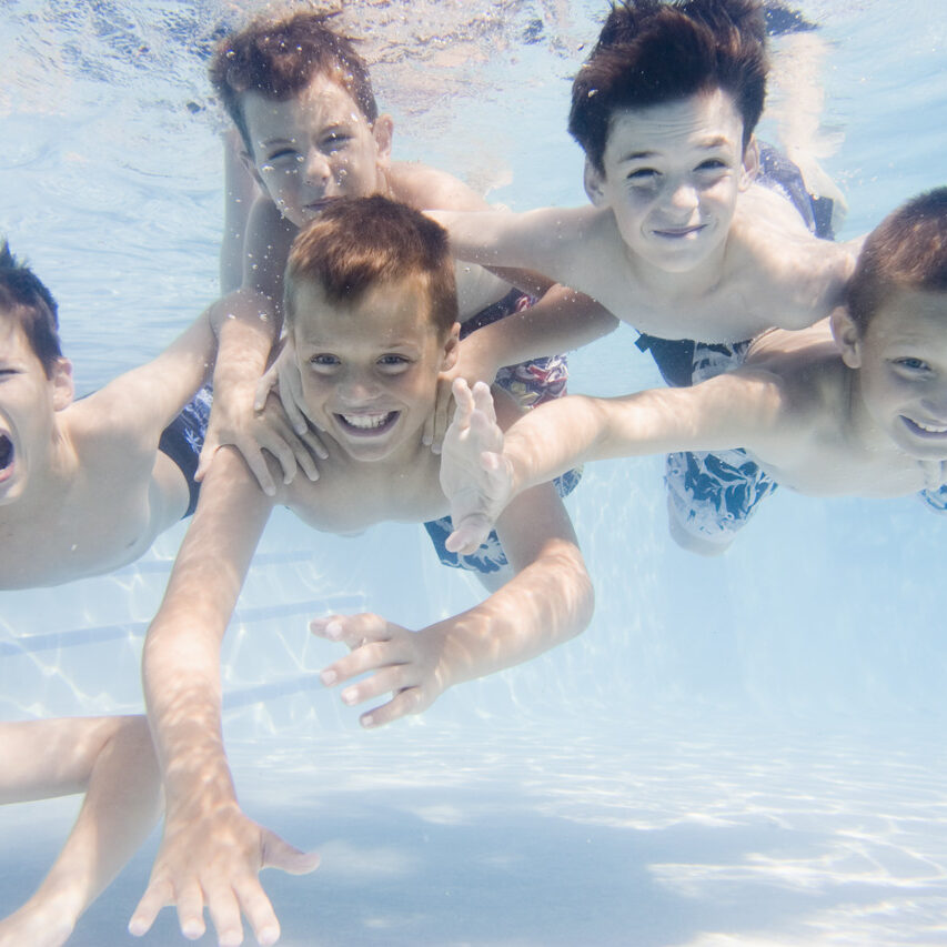 Friends Swimming Underwater in Backyard Pool --- Image by © Royalty-Free/Corbis